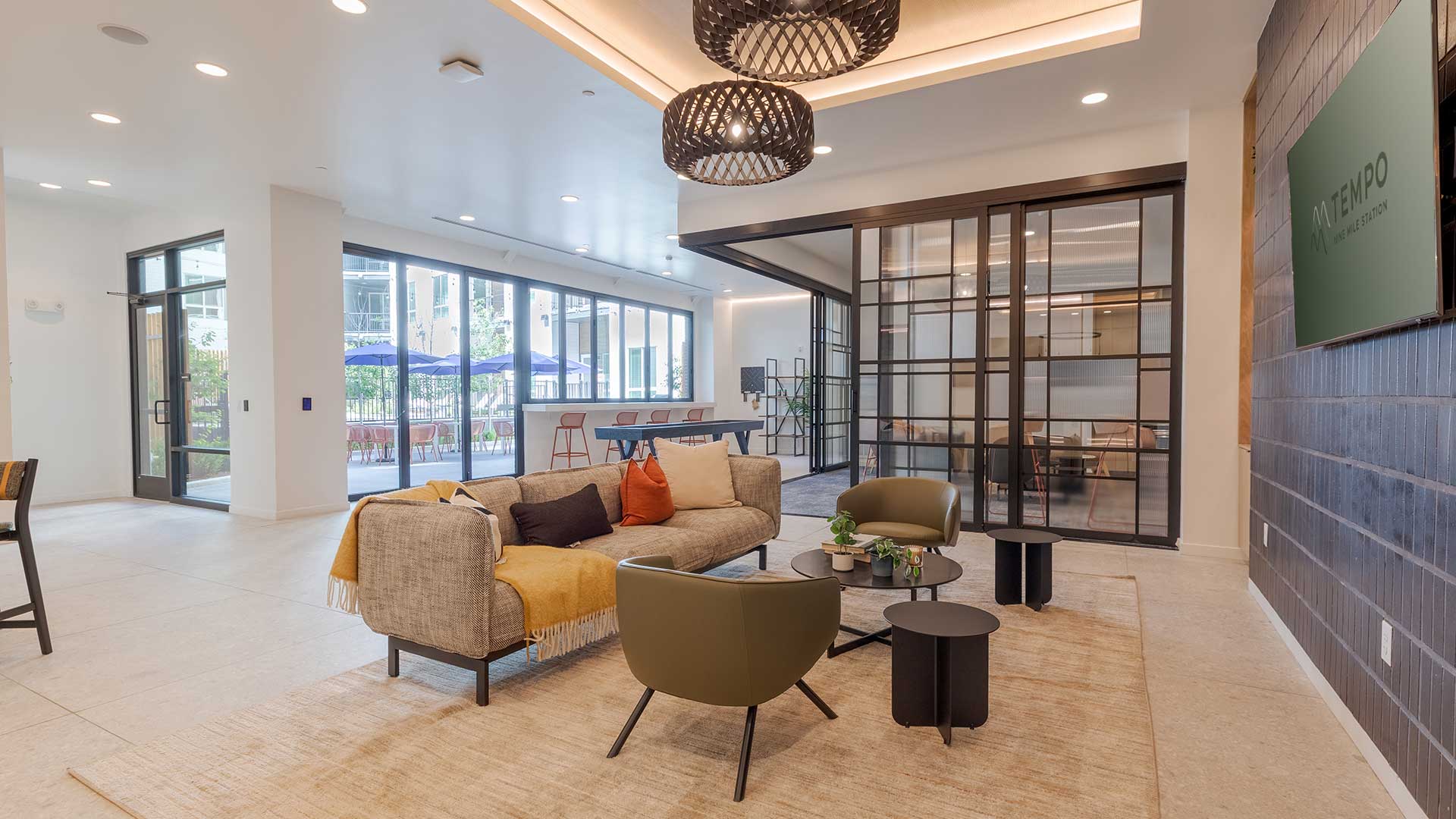 Modern resident social lounge with seating areas, coworking rooms, and contemporary finishes at Tempo at Nine Mile apartments.