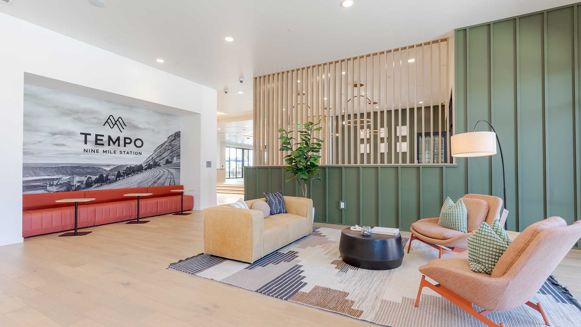 Modern resident lounge with contemporary seating, wood accents, decorative lighting, and Tempo at Nine Mile branding inside the apartment community clubhouse.