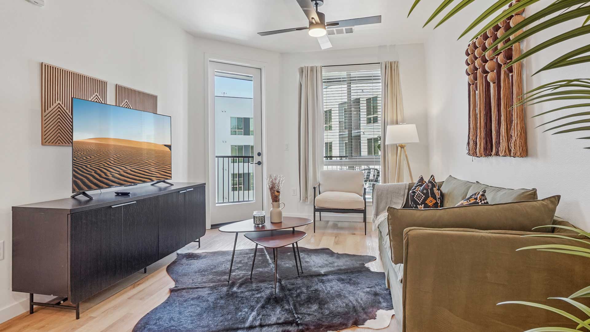 Modern apartment living room with balcony access, contemporary furnishings, and natural light at Tempo at Nine Mile.