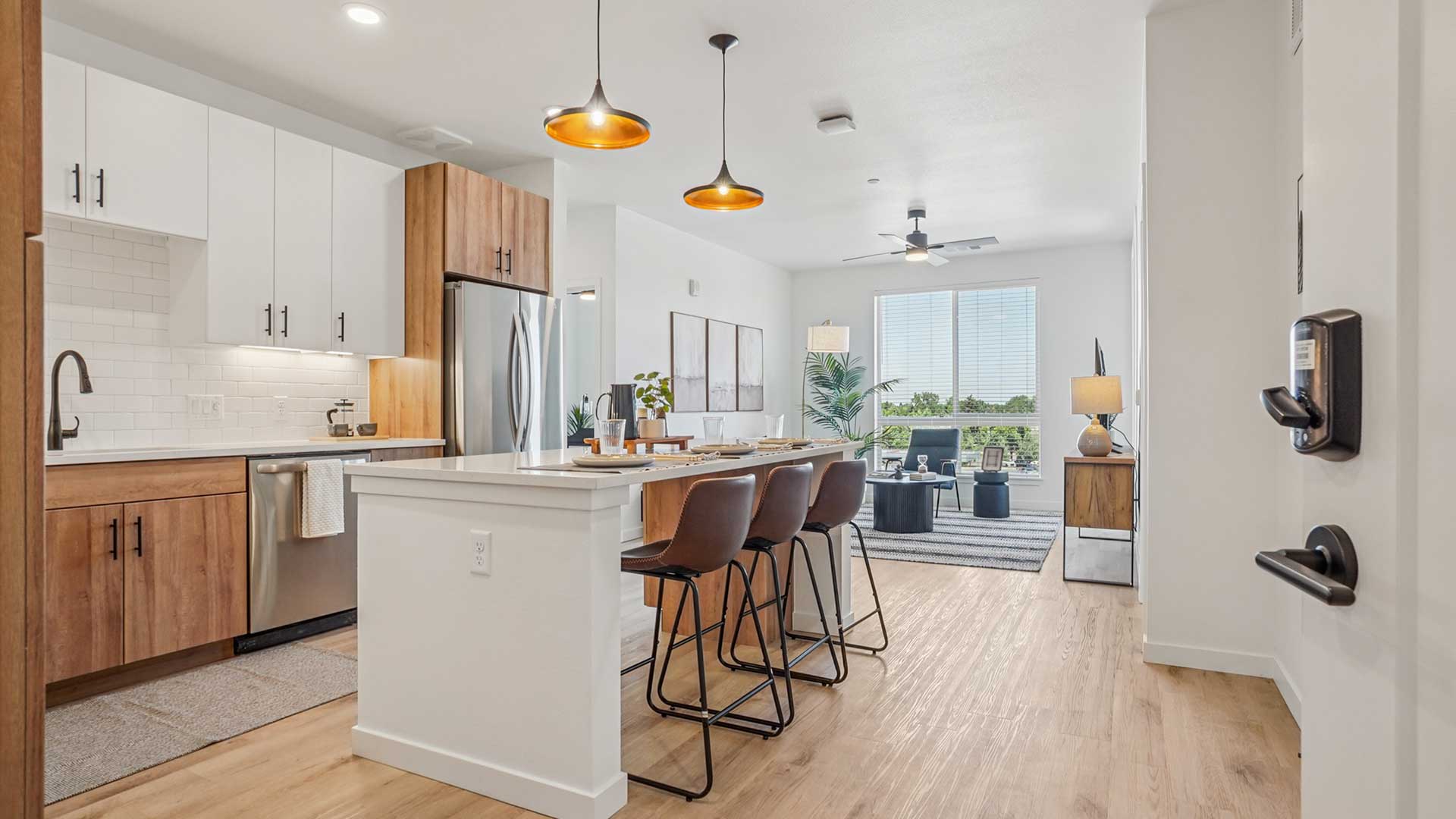 Modern open-concept apartment with kitchen island, stainless-steel appliances, and spacious living area at Tempo at Nine Mile.