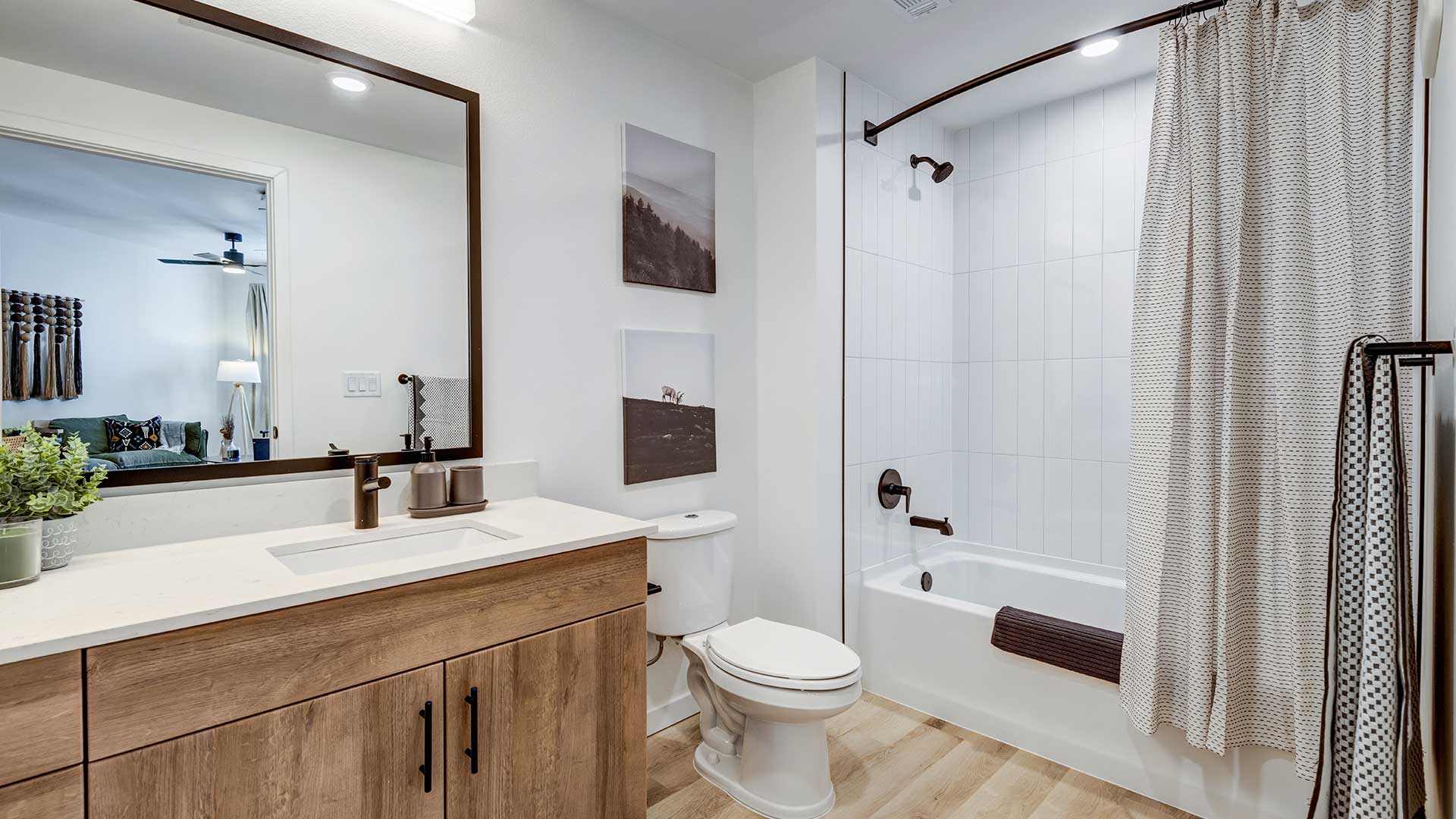 Modern apartment bathroom with wood-style vanity, contemporary fixtures, and tiled shower at Tempo at Nine Mile.