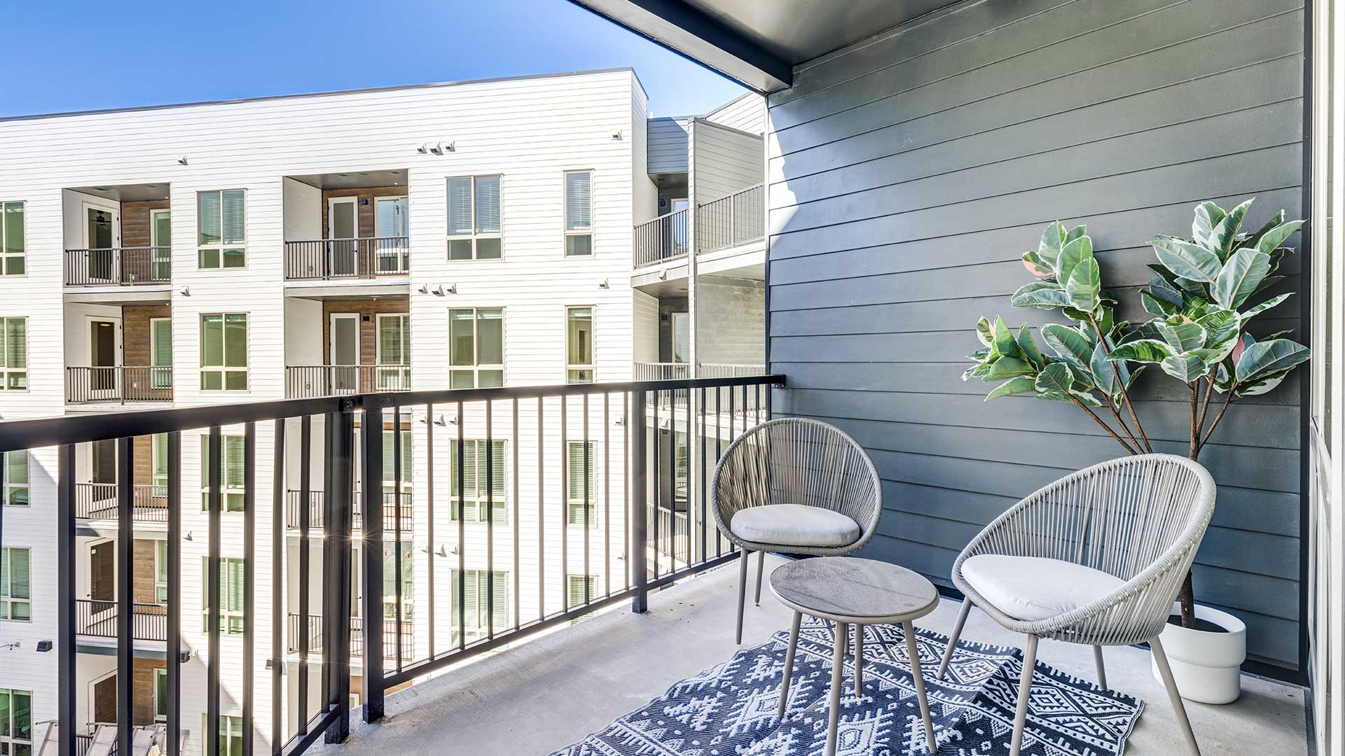 Private apartment balcony with seating area overlooking the courtyard at Tempo at Nine Mile apartments.