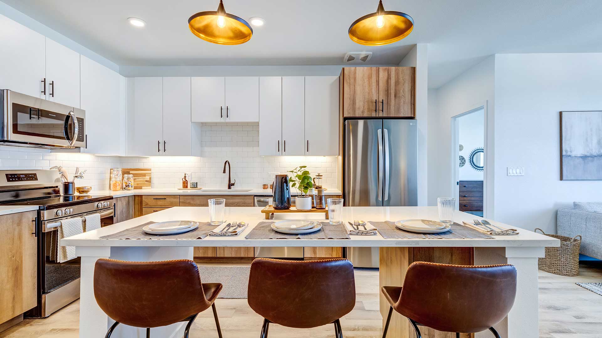 Modern apartment kitchen at Tempo at Nine Mile with a large island, pendant lighting, stainless steel appliances, and seating for four.
